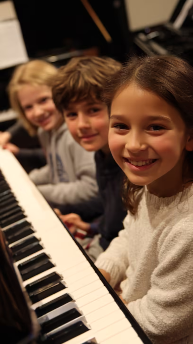 Smiling children enjoying a group piano lesson at K&M Music School in San Diego