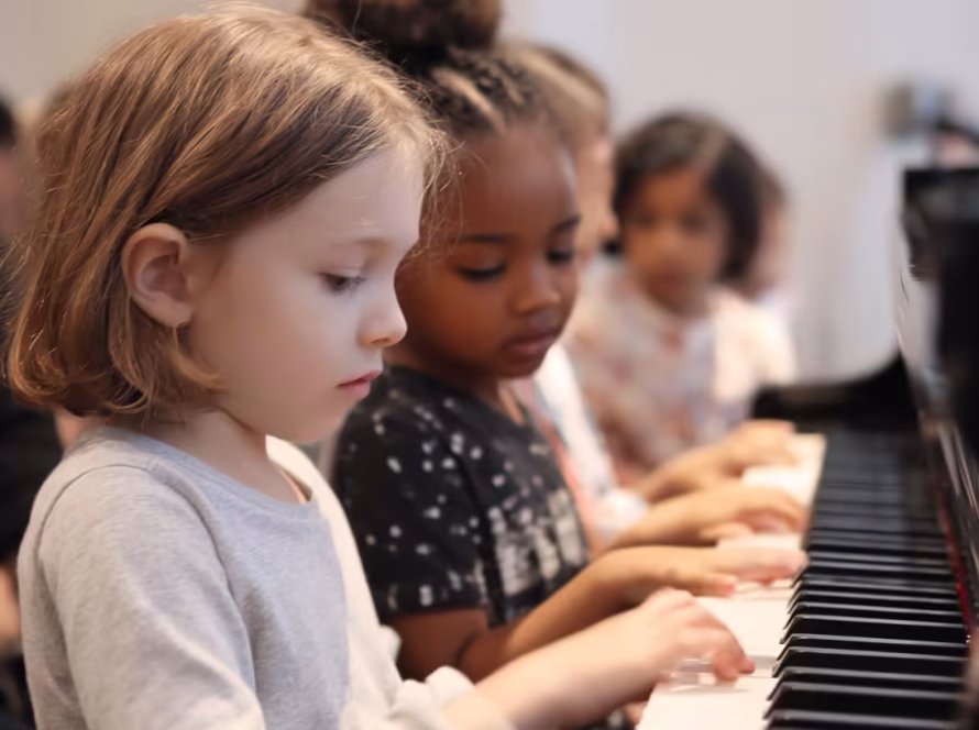 Two young children learning teamwork while playing piano together
