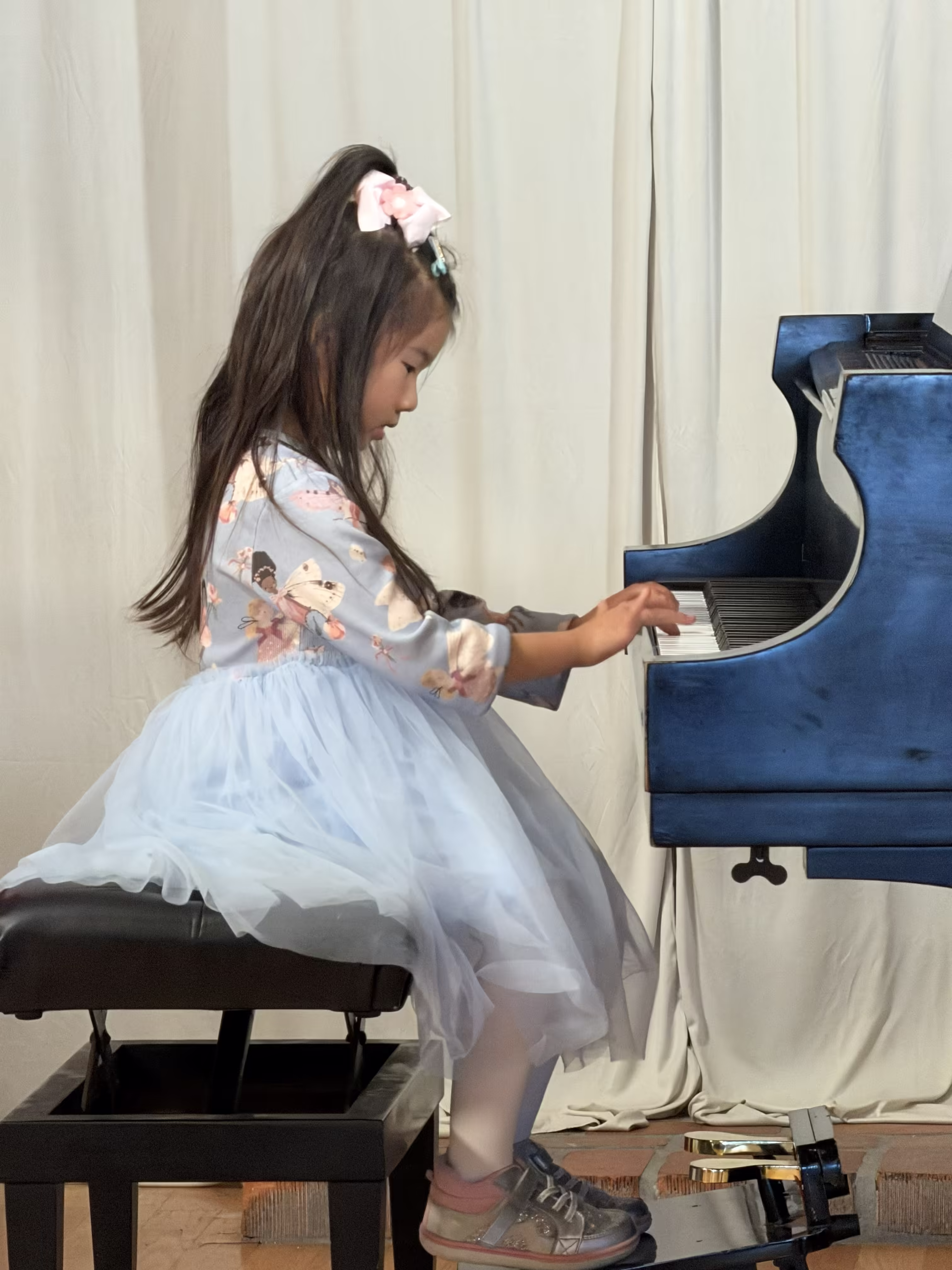 Young girl performing on a grand piano at a K&M Music School recital in San Diego