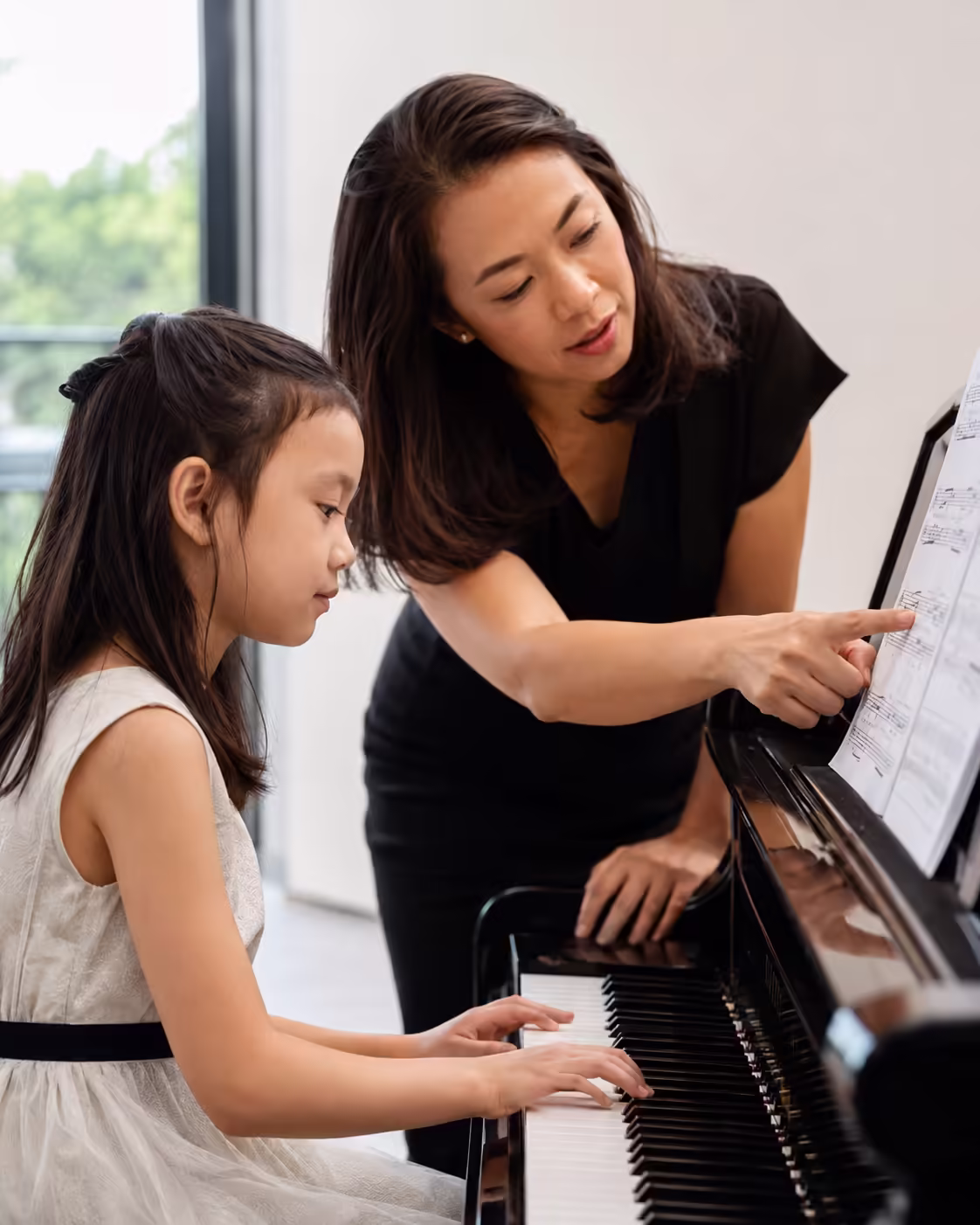 Teacher giving piano instruction to a child during a music lesson