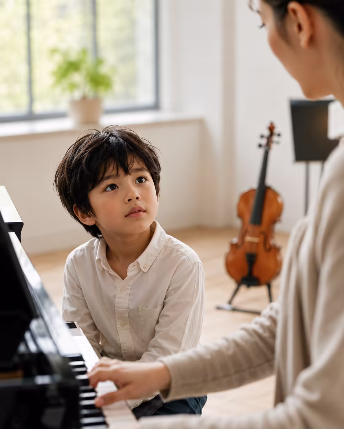 Child listening intently to a teacher play piano